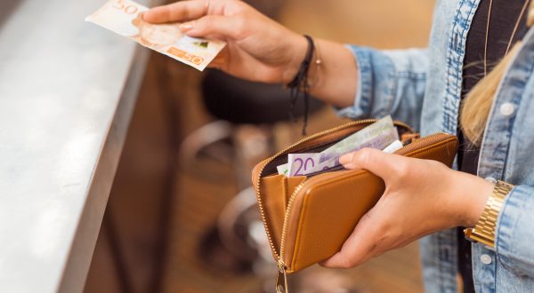 Eine Frau mit einer Geldtasche in der Hand bezahlt mit Bargeld