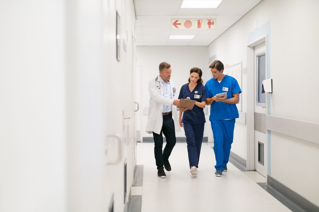 Arzt sieht mit einer Krankenschwester und einem Pfleger auf einen Bericht