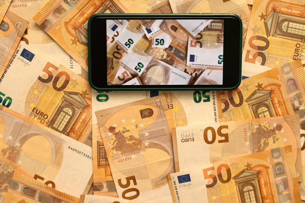 Handy wird über viele 50-Euro-Scheine gehalten