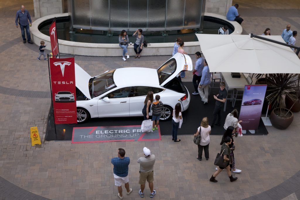 Auto von Tesla mit vielen Menschen rundherum