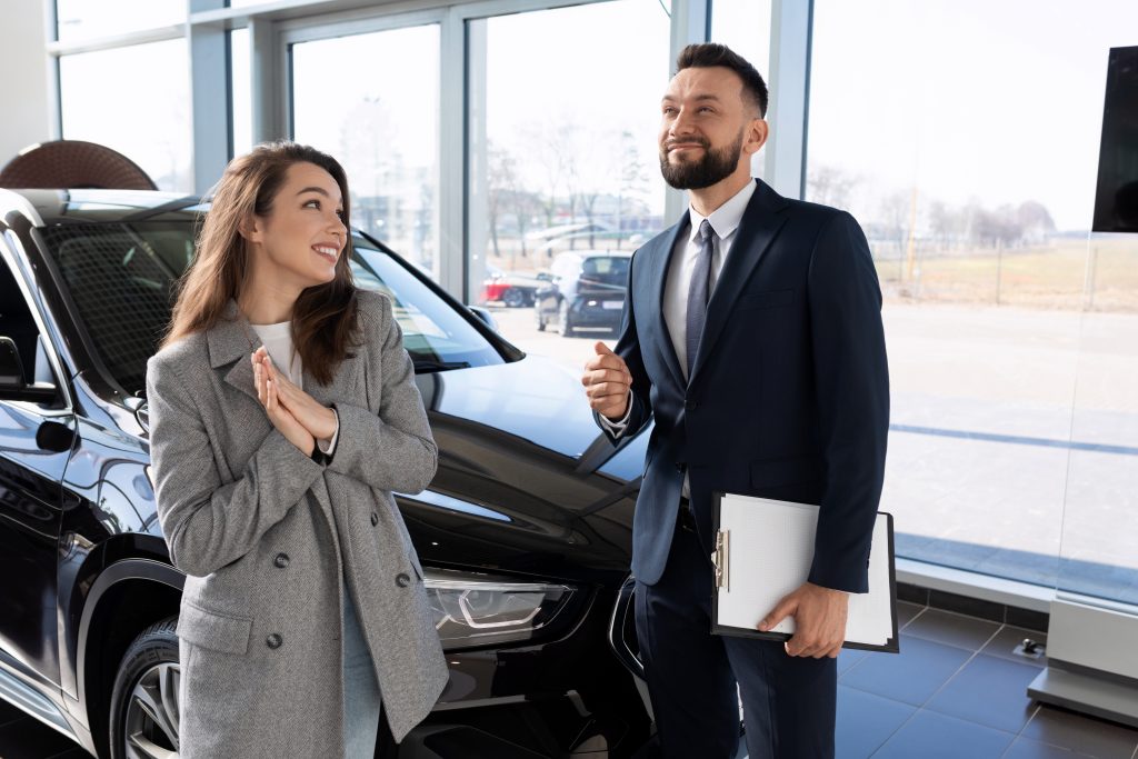 Junge Frau die einen Autoverkäufer im Anzug anlächelt
