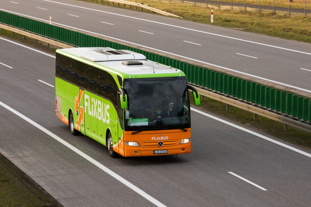 Flixbus in grün und orange der auf einer Autobahn in Richtung Kamera fährt. 