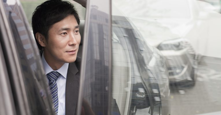 Chinesischer Mann sitzt in einem Auto und sieht aus dem Fenster