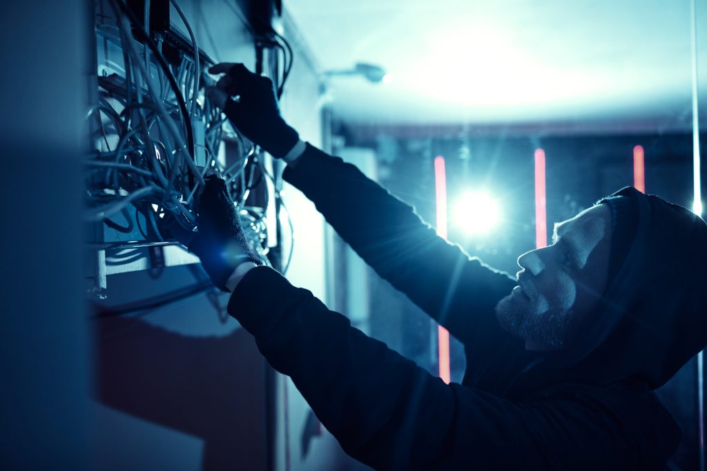 Mann in dunkler Kleidung und Handschuhen arbeitet an einem Stromverteiler
