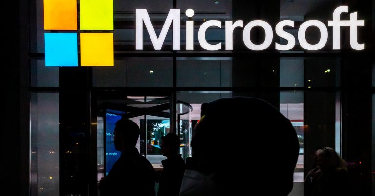 Logo von Microsoft über dem Eingang in ein Büro bei Nacht beleuchtet