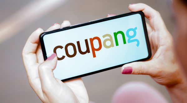 Person hält Telefon mit Coupang-Logo in den Händen