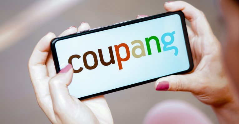Person hält Telefon mit Coupang-Logo in den Händen