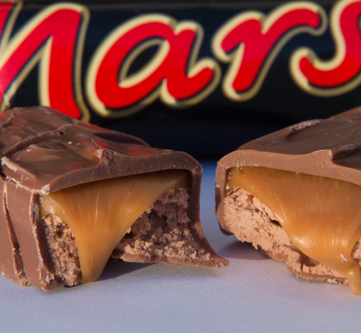 Zwei angebrochene Mars-Riegel und dahinter Mars in einer Verpackung
