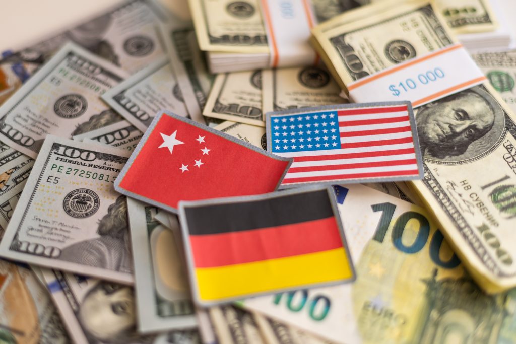 Die Flaggen von China, Amerika und Deutschland liegen auf mehreren Dollarnoten