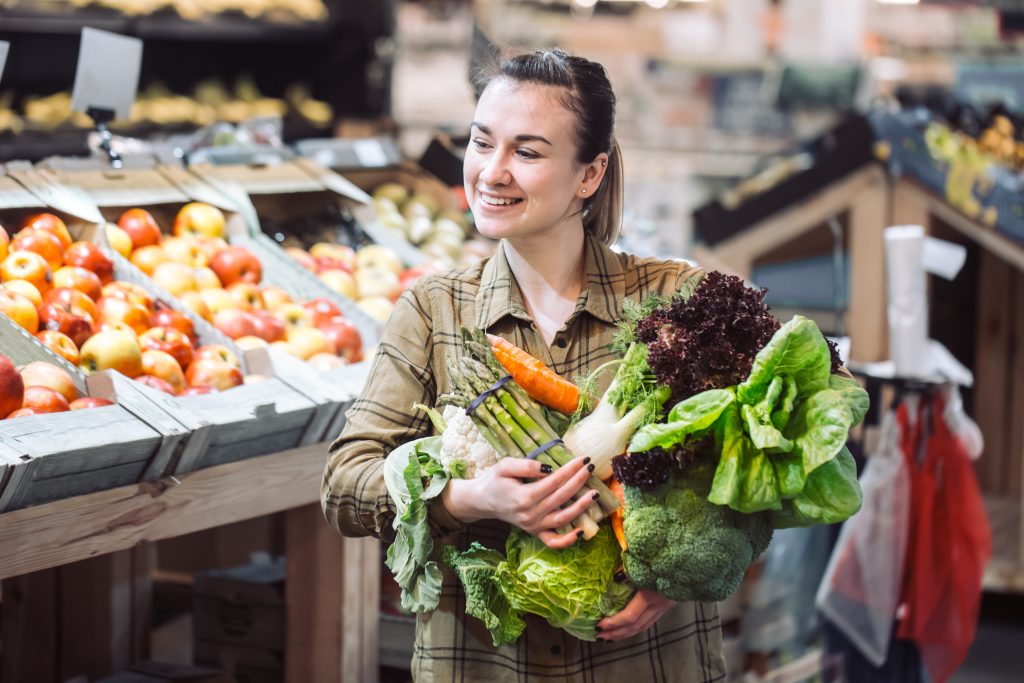 Frau in Supermarkt hält Gemüse in den Händen