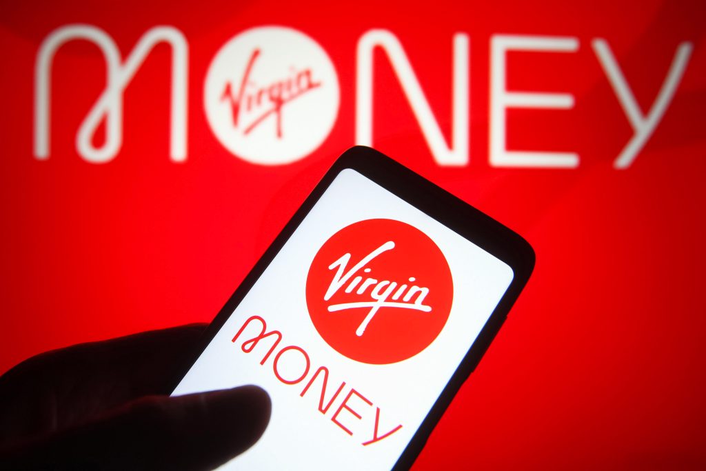 Roter Hintergrund mit dem Logo von Virgin Money. Davor ein Handy das ebenfalls das Logo Virgin in einem roten Kreis zeigt und darunter auf weißem Hintergrund die Buchstaben Money