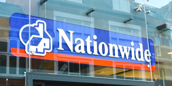Logo von Nationwide in blau mit einem roten Strich darunter auf dem Eingang zu einem Gebäude aus Glas