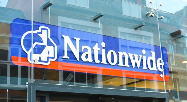 Logo von Nationwide in blau mit einem roten Strich darunter auf dem Eingang zu einem Gebäude aus Glas