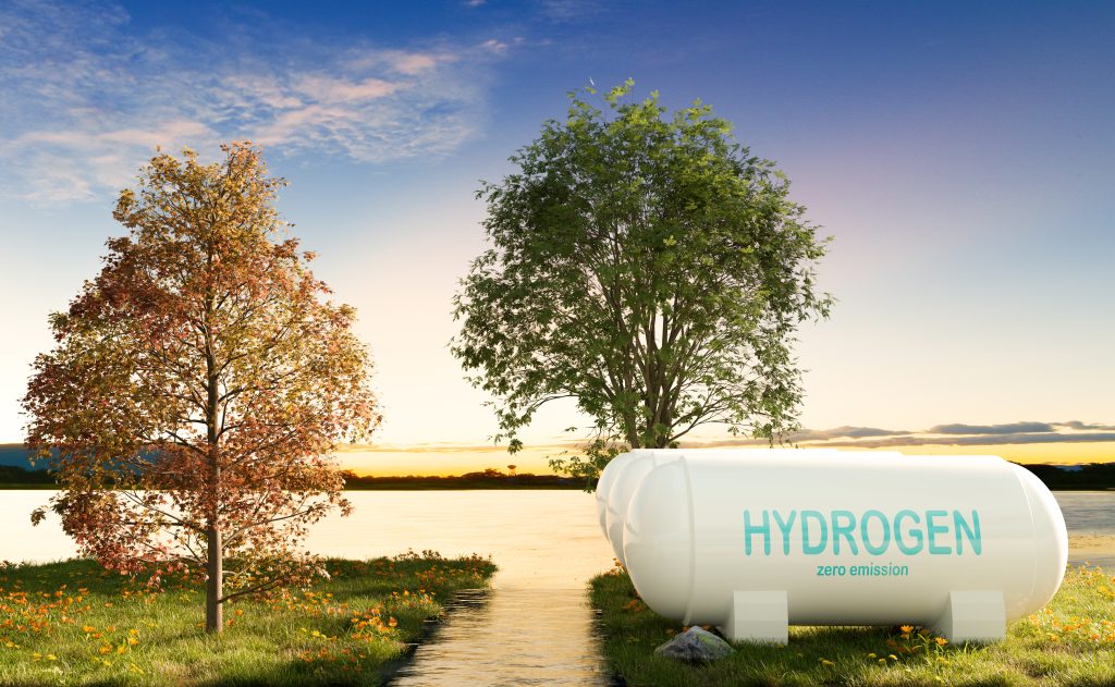 Wasserstoff-Tank mit der Aufschrift Hydrogen zero emission steht vor zwei Bäumen. Dahinter ein Sonnenuntergang