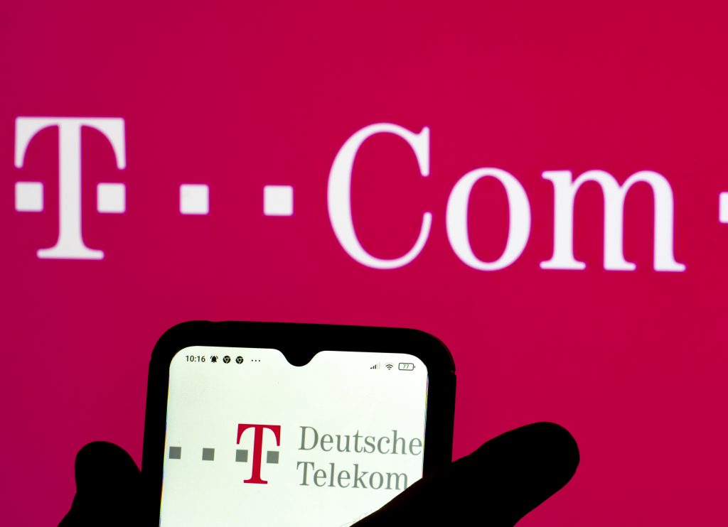 roter Hintergrund und Logo der Deutschen Telekom. Davor ein Handy ebenfalls mit dem Logo 
