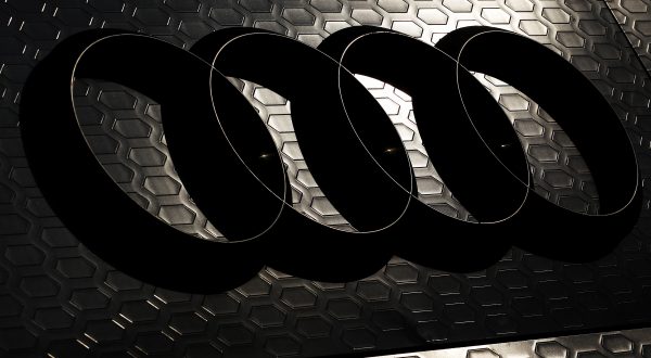 Logo von Audi mit vier Ringen auf einem dunkelgrauen Hintergrund