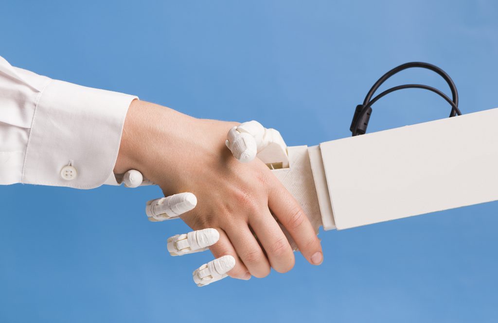Menschliche Hand gibt einer Computer-Hand die Hand