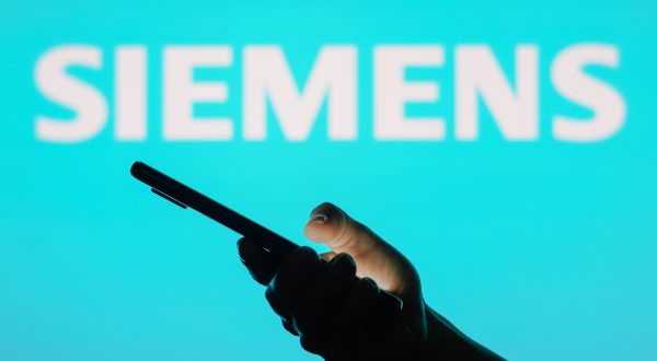 Logo von Siemens davor eine Hand die ein Handy hält