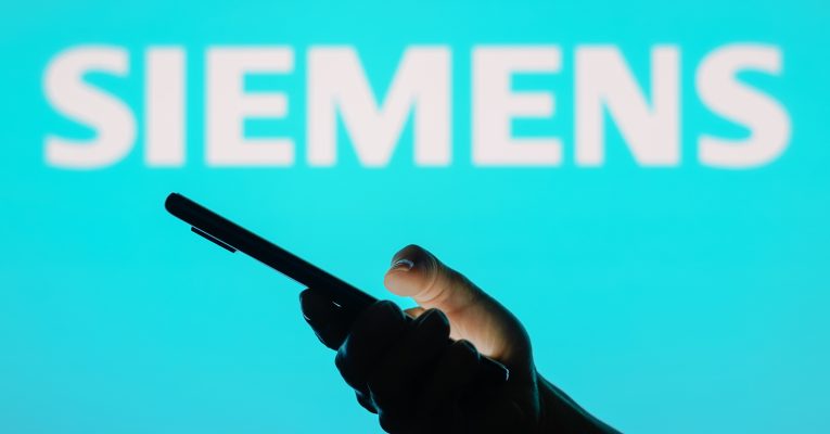 Logo von Siemens davor eine Hand die ein Handy hält
