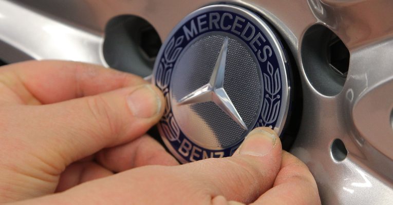 Mercedes-Stern der von zwei Händen gehalten wird