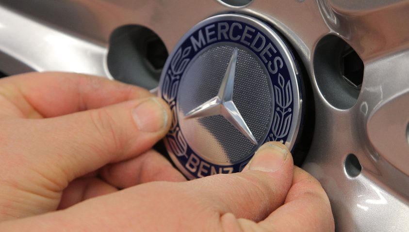 Mercedes-Stern der von zwei Händen gehalten wird