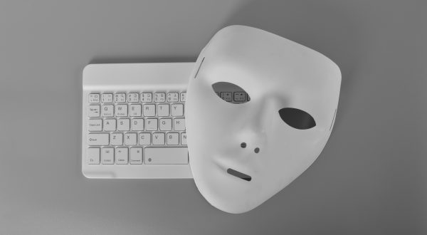Laptop-Tastatur und anonyme Maske. Datendieb, Internetbetrug, Cyberangriff, Cybersicherheitskonzept.