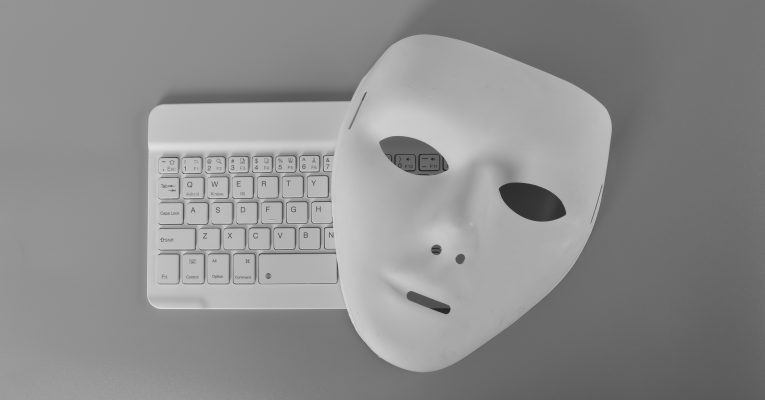 Laptop-Tastatur und anonyme Maske. Datendieb, Internetbetrug, Cyberangriff, Cybersicherheitskonzept.