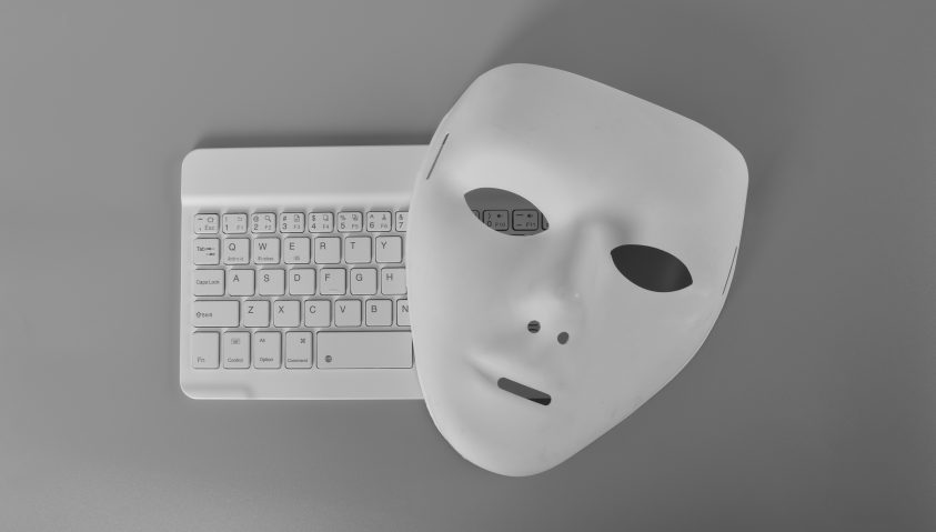 Laptop-Tastatur und anonyme Maske. Datendieb, Internetbetrug, Cyberangriff, Cybersicherheitskonzept.