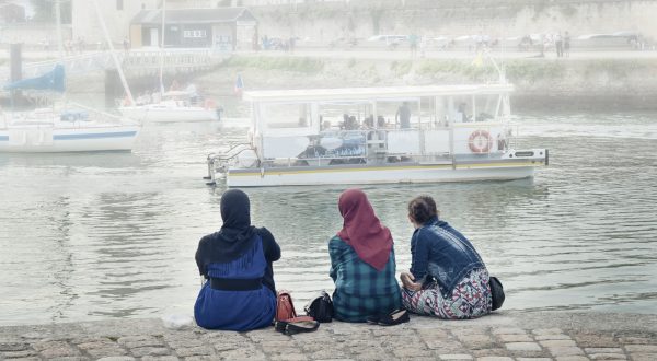 Mehrere Flüchtlinge sitzen am Hafen