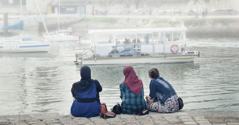 Mehrere Flüchtlinge sitzen am Hafen