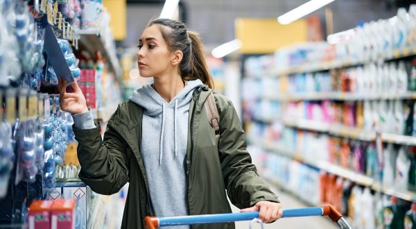 Frau steht in einem Supermarkt und schaut sich Produkte an