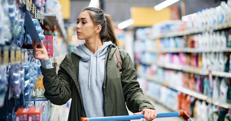 Frau steht in einem Supermarkt und schaut sich Produkte an